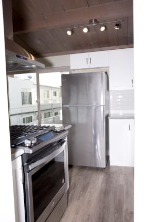 Kitchen with stainless steel appliances and hardwood floor at Harbor Villa Apartments in San Diego, California.