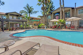A swimming pool surrounded by lounge chairs and umbrellas.