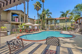 A pool surrounded by a patio and chairs.