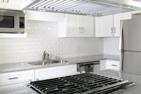 Kitchen with gas range, microwave, dishwasher, and refrigerator at Harbor Villa Apartments in San Diego, California.