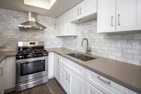 A modern kitchen with a stainless steel oven and white cabinets.