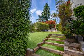 A wooden garden pathway leads through a lush green lawn.