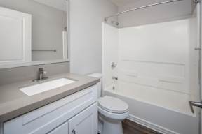 A white bathroom with a toilet, sink, and bathtub.