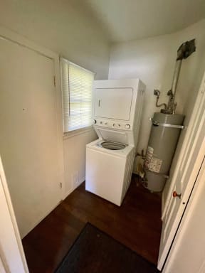 Laundry room with stacked washer and dryer at Orange Grove Apartments in Pasadena, CA.
