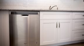 Kitchen with dishwasher and spacious white cabinets at Harbor Villa Apartments in San Diego, California.