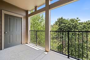 A balcony with a black railing and a grey door.
