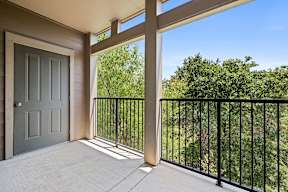 A balcony with a black railing and a grey door.