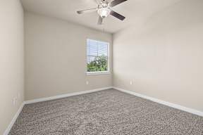 A room with a ceiling fan and carpeted floor.