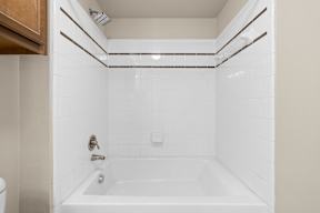 A white bathroom with a tub and toilet.