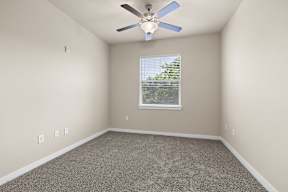 A room with a ceiling fan and a window with blinds.