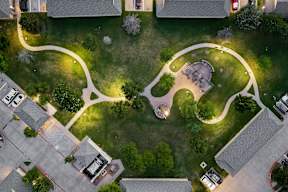 A park with a circular pathway and a building in the background.