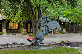 A statue of a man riding a horse is in front of a house.