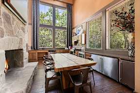 A dining room with a stone fireplace and a wooden table.