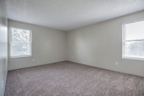 an empty room with carpet and two windows