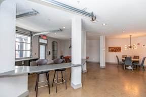 A modern open plan living and dining area with a kitchen island and bar stools.