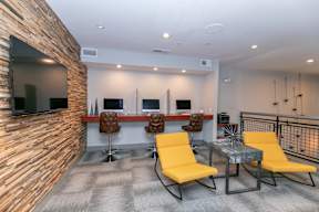 A room with a stone wall and a table with yellow chairs.