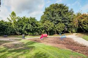 A playground with a red slide and a blue swing set.