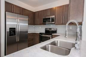 A kitchen with a stainless steel refrigerator, microwave, oven, and sink.