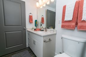 A white bathroom with a grey door and a white tub.