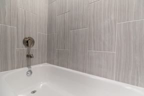 A white bathtub with a silver faucet and a silver shower head.