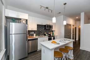 A modern kitchen with a white island and stainless steel appliances.