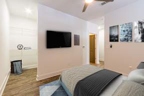 A bedroom with a bed, a television, and a ceiling fan.