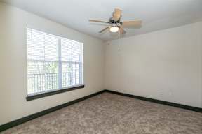 A room with a ceiling fan and a window with blinds.