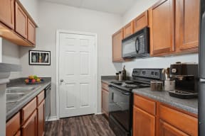 a kitchen with wood cabinets and black appliances and a white door
