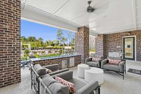 A patio with a grey couch and a white table.