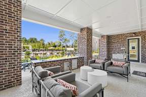 A patio with a white couch and a grey couch with a red and white throw on it.