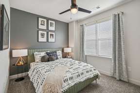 A bedroom with a bed, two lamps, and a ceiling fan.