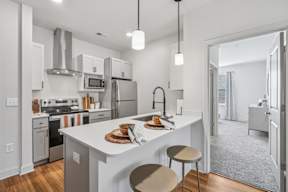 A modern kitchen with a white island and stainless steel appliances.