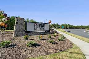 A sign for Heviq Riverview in front of a road.