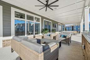 A patio with a couch, chairs, and a ceiling fan.