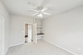 an empty bedroom with a ceiling fan and a closet