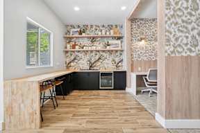 A kitchen with a wooden bar and black cabinets.