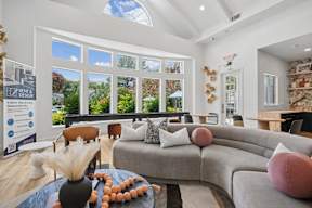 A living room with a grey sofa and a table with a vase and some decorations on it.