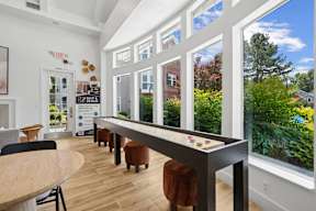 A room with a long table and chairs with a view of the backyard through the windows.
