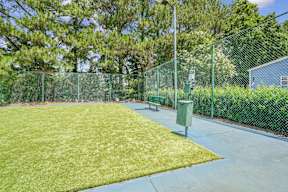 A green fenced area with a bench and a trash can.