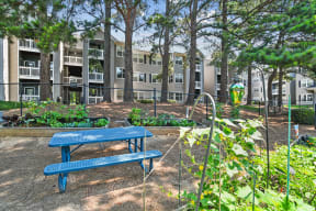 a blue picnic table in a garden in front of an apartment building