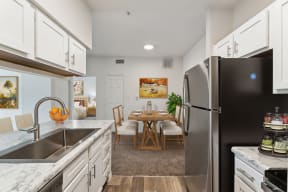 an open kitchen and dining room with stainless steel appliances and white cabinets