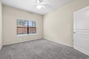 A room with a ceiling fan and a window with blinds.