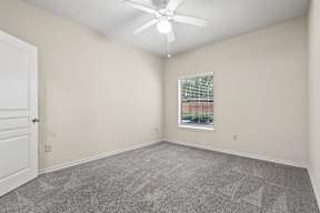 A room with a ceiling fan and a window with blinds.