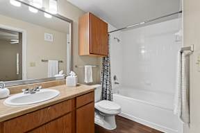 A white toilet is in a bathroom with a wooden vanity.