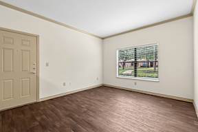 A room with a wooden floor and a window showing a view of a street.