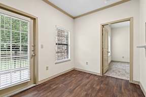 A room with wooden floors and a doorway leading to another room.
