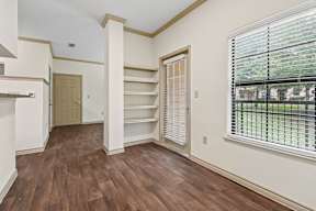 A room with wooden floors and a window with blinds.
