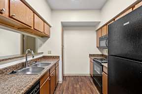 A kitchen with a black refrigerator and wooden cabinets.