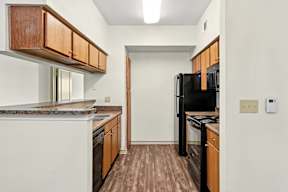 A kitchen with wood cabinets and black appliances.