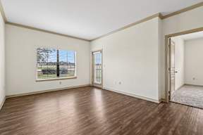 A room with wooden floors and a window with blinds.